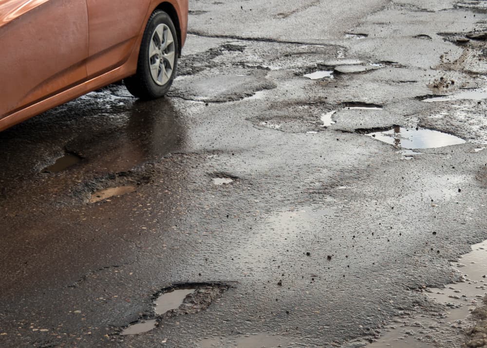 Hole in the asphalt on a damaged road, highlighting the risk of driving.