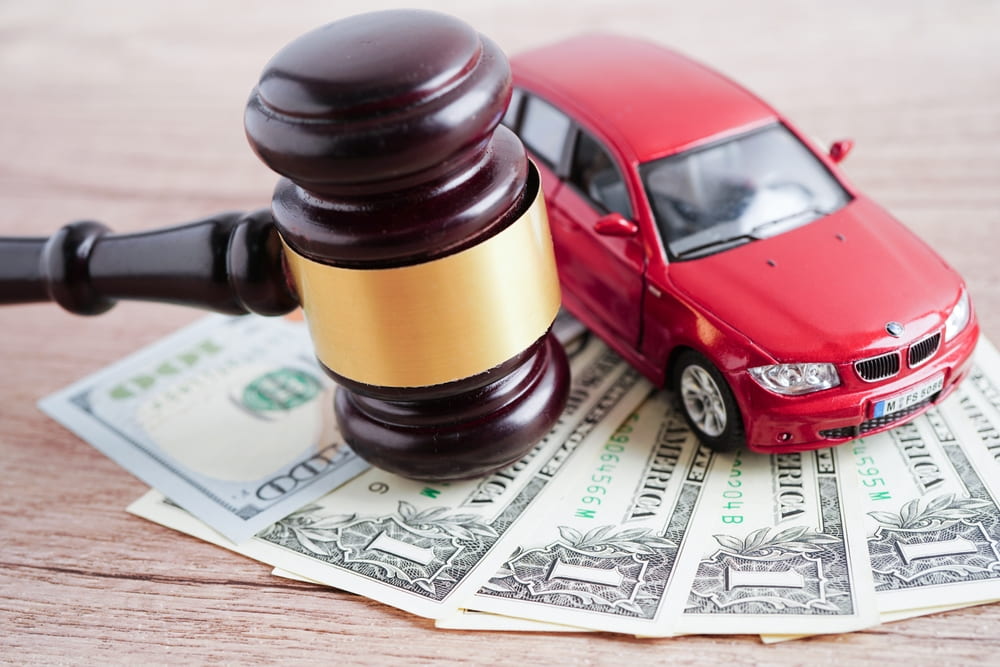 An image showing a car, a judge’s gavel, and money bills to represent what questions you should ask a car accident attorney