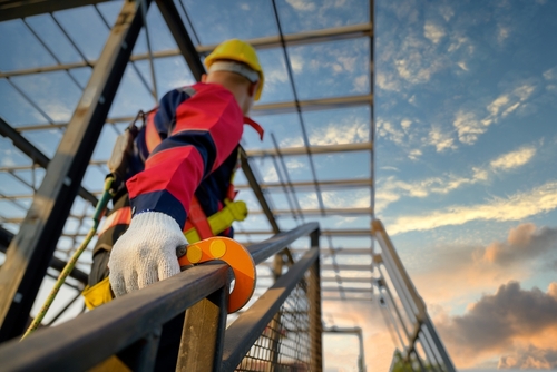 Male construction worker working at height, wearing safety gear and safety harness, demonstrating the importance of an Employment Law Lawyer