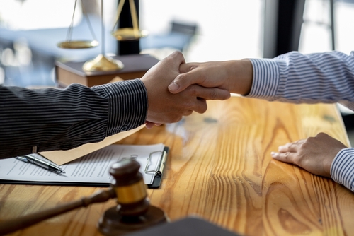 An image showing an attorney and a client shaking hands to represent what questions you should ask your car accident attorney and the importance of good communication