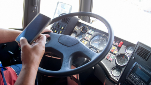 A truck driver inside his truck using his phone, suggesting he is discussing the accident on social media, which is one thing you shouldn’t do after a truck accident