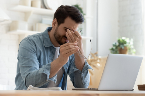 Frustrated man sitting at a desk with a laptop, representing the need for wage hour lawyers