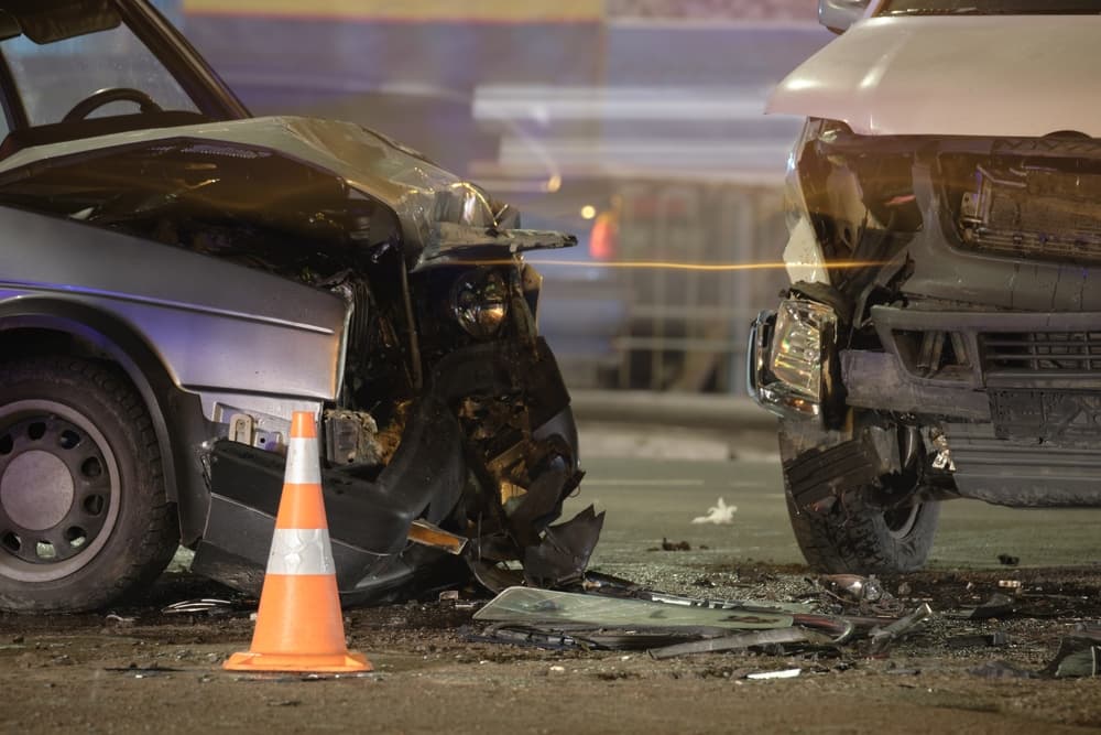 Damaged in heavy car accident vehicles after collision on city street crash site at night