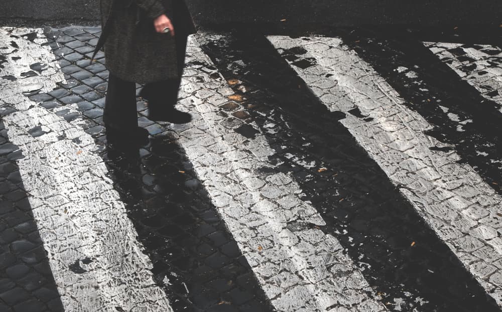 A woman walking on poorly maintained crosswalk.